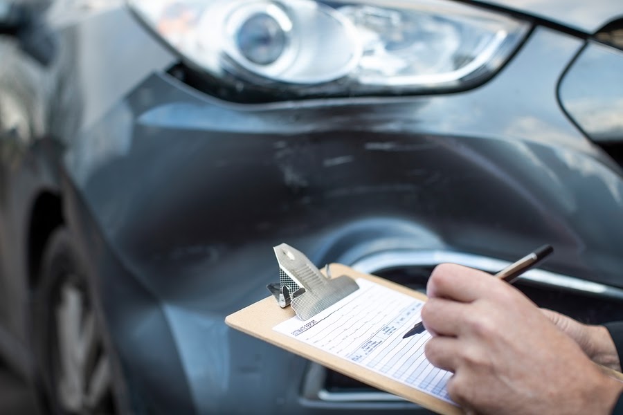 car with dent that needs removal and person with clipboard, paper and pen